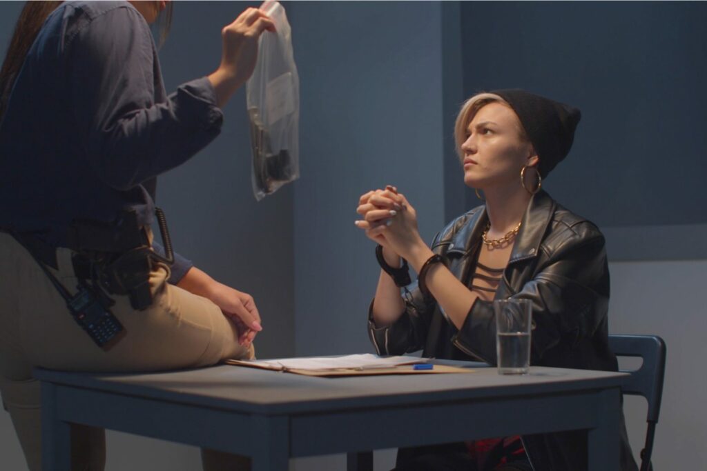 A cop shows a woman a gun as evidence.