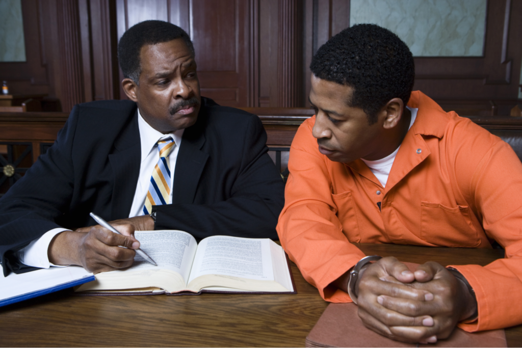 Middle aged advocate sitting with criminal in the courtroom